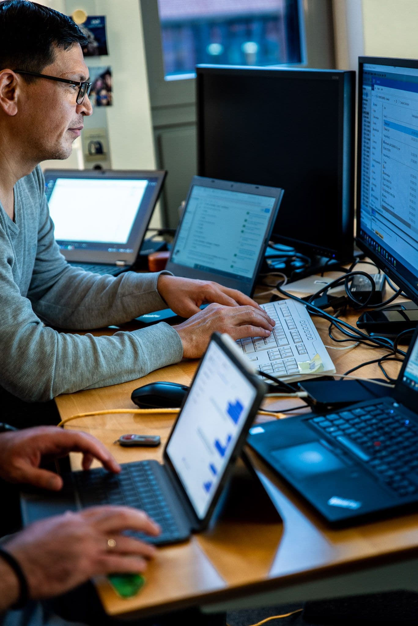 2 Personen arbeiten nebeneinander sitzend an einem Schreibtisch am Computer